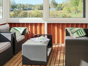 A covered outdoor seating area with wicker furniture and a view of a green landscape. - 6 Person Holiday Home in Mellbystrand (Mellbystrand)