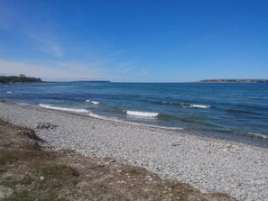 A pebble beach with clear blue water and distant land. - 4 Star Holiday Home in Klintehamn (Klintehamn)