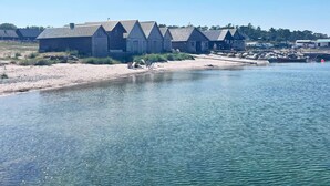 Una propiedad frente al agua con varios edificios de madera, una playa arenosa y una masa de agua tranquila.