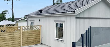 A single-story building with a tiled roof, a wooden fence, and a gravel driveway.