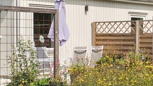 A residential building with a metal roof, a wooden fence, and a garden with various plants and flowers. - 4 Star Holiday Home in Klintehamn (Klintehamn)