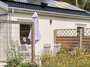 A residential building with a metal roof, a wooden fence, and a garden with various plants and flowers. - 4 Star Holiday Home in Klintehamn (Klintehamn)