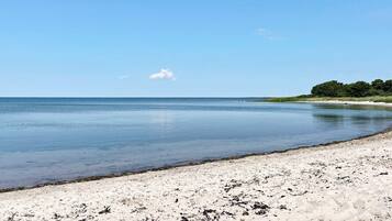 Una playa con arena y aguas tranquilas.