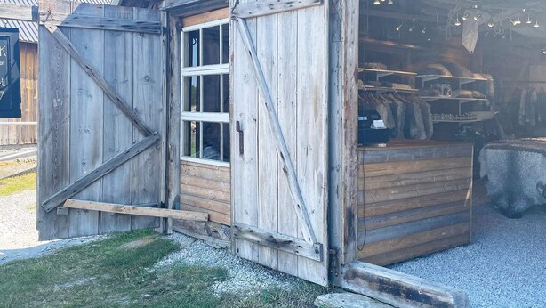 A rustic wooden building with a large open garage door, a window, and a gravel driveway. - 4 Star Holiday Home in Klintehamn (Klintehamn)
