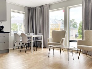 A modern living room with a dining area, large windows, and a view of the outside. - 4 Star Holiday Home in Klintehamn (Klintehamn)