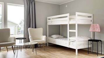Una habitación con literas, una silla, una mesita y una lámpara.