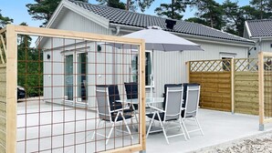 Un patio con una mesa, sillas, una sombrilla y una valla de madera.