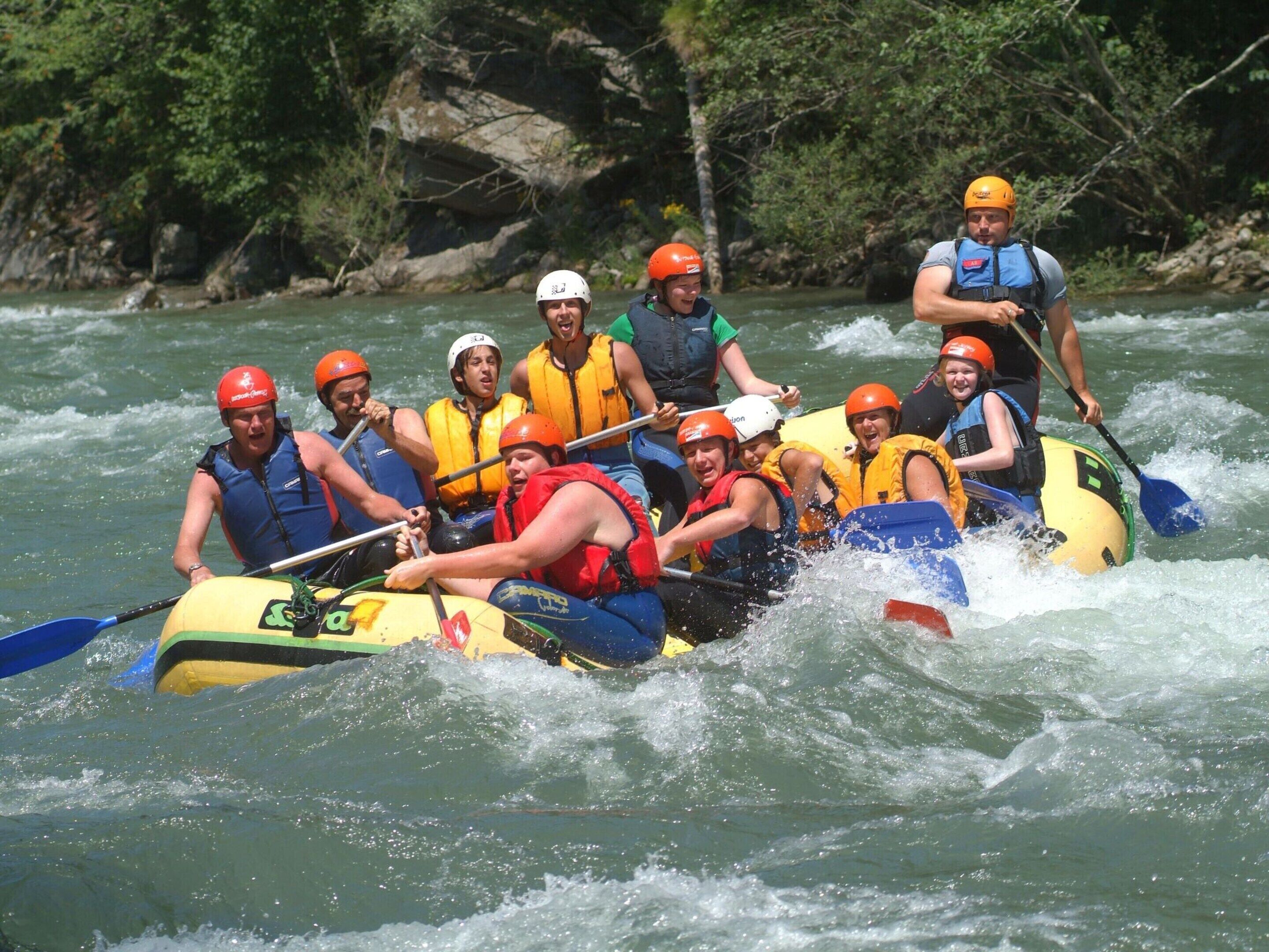 A group of people in a raft navigating through a river surrounded by greenery.