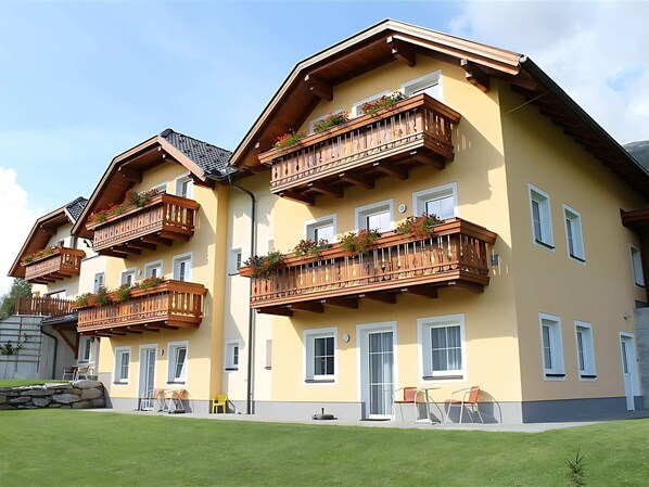 A multi-story building with balconies, windows, and a stone wall. - Apartment in Lungau Near Ski Lift (Sankt Michael im Lungau)