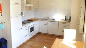 A modern kitchen with white cabinetry, a wooden countertop, a built-in oven, a dishwasher, and a sink. - Apartment in Lungau Near Ski Lift (Sankt Michael im Lungau)