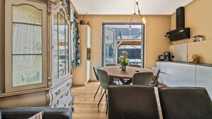 Un coin repas avec une table en bois, des chaises et un vase de fleurs. On y trouve également un meuble avec des portes en verre et une statue de lion décorative sur le dessus.