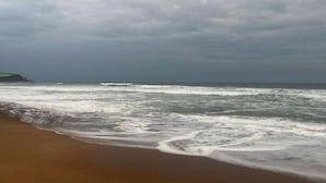 Una playa con olas rompiendo en la orilla bajo un cielo nublado.