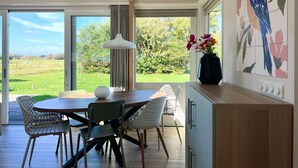 Eine moderne Küche mit Essbereich, großen Fenstern und Blick ins Freie.