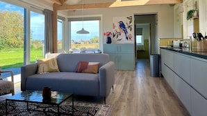 Ein modernes Wohnzimmer mit einem grauen Sofa, einem Couchtisch und Blick ins Freie.