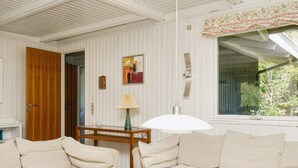 A cozy room with two beige sofas, a wooden coffee table, and a window with a view of greenery. - 6 Person Holiday Home in Gilleleje (Gilleleje)