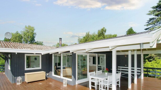 A modern house with a wooden deck, large windows, and a covered patio area. - 6 Person Holiday Home in Gilleleje (Gilleleje)