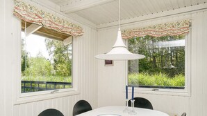 A dining area with a white table, black chairs, and a hanging white pendant light. - 6 Person Holiday Home in Gilleleje (Gilleleje)