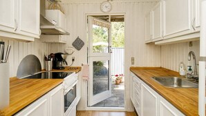 A compact kitchen with white cabinetry, wooden countertops, a built-in oven, and a double sink. - 6 Person Holiday Home in Gilleleje (Gilleleje)