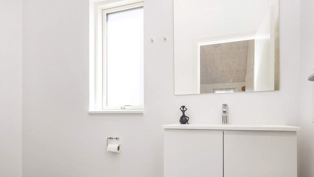 Un bagno con il water, una finestra, uno specchio e un armadietto.