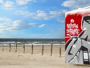 Una playa con un cartel que dice 'SEKTION DIARRHOE' y vista al océano.