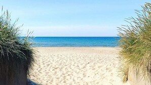 Un sentiero di sabbia che conduce all'oceano, costeggiato da erba su entrambi i lati.