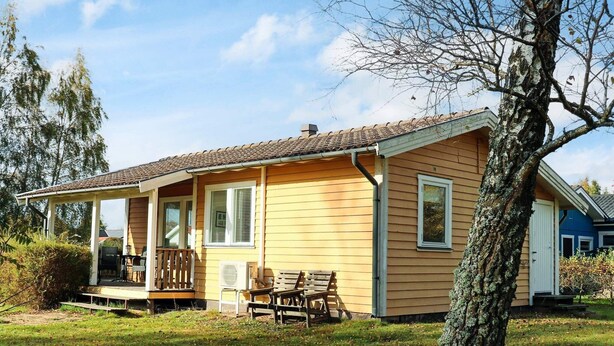 Una casa a un piano con veranda, un piccolo patio e un prato.