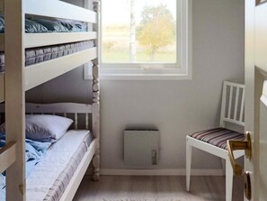 Une chambre avec un lit superposé, une fenêtre, une chaise et un radiateur.