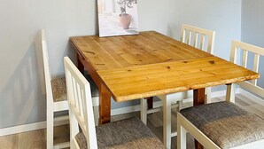 Una mesa de comedor de madera con cuatro sillas blancas, cada una con asiento acolchado.