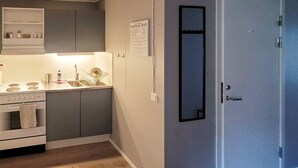 Cocina compacta con estufa, lavaplatos y refrigerador de pared.