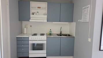 A compact kitchen with a stove, oven, and sink, featuring grey cabinets and a white countertop.