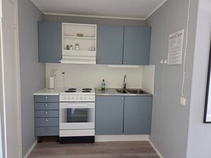 A compact kitchen with grey cabinets, a white stove, and a sink. - 4 Person Holiday Home in Nosund (Nosund)