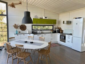 A modern kitchen with white cabinets, a black pendant light, and a Bosch refrigerator. - 7 Person Holiday Home in Jarna (Järna)