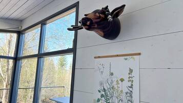 A room with a mounted animal head on the wall, a large window, and a botanical illustration.