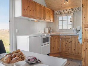 Eine Küche mit Holzschränken, einem weißen Herd und einem Fenster mit Blick ins Freie.
