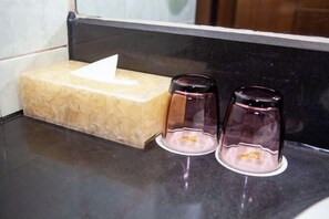 A bathroom counter with a beige soap dish and two purple glass containers. - Long Shao Heng Hotel (Beijing)