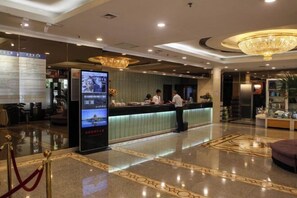 A hotel lobby with a reception desk, a digital information board, and a chandelier. - Long Shao Heng Hotel (Beijing)