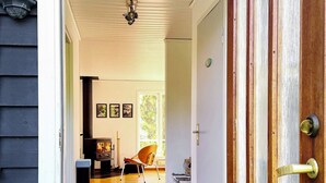 A wooden interior with a fireplace, a chair, and a door with a brass handle. - 4 Star Holiday Home in Hoviksnas (Höviksnäs)