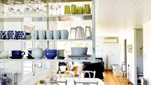 A modern kitchen with white cabinetry, a wooden dining table, and various kitchenware. - 4 Star Holiday Home in Hoviksnas (Höviksnäs)