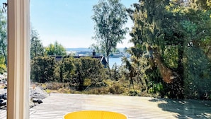 A wooden deck with a yellow cylindrical object, overlooking a body of water and dense greenery. - 4 Star Holiday Home in Hoviksnas (Höviksnäs)