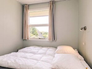 A single bed with white bedding in a room with light-colored walls and a window with curtains. - 6 Person Holiday Home in Brenderup Fyn (Middelfart)