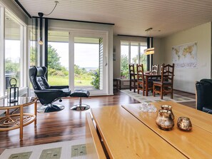 A spacious room with a large wooden table, a black leather chair, and a dining area with wooden chairs. - 6 Person Holiday Home in Brenderup Fyn (Middelfart)