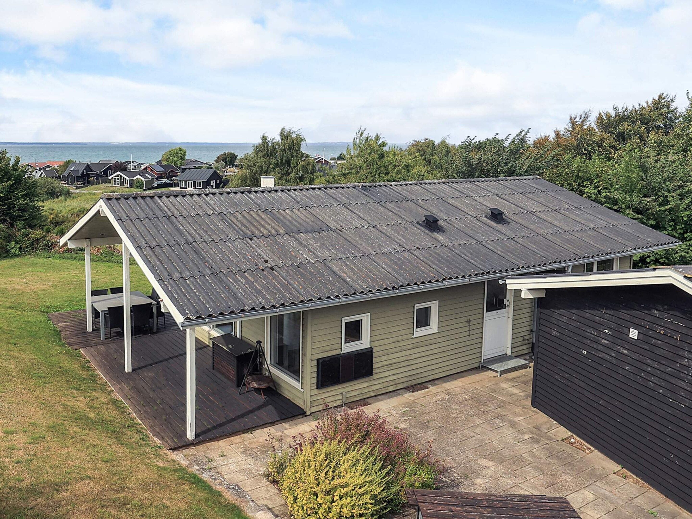 A single-story house with a covered patio, a garage, and a view of the sea.