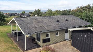 A single-story house with a covered patio, a garage, and a view of the sea.