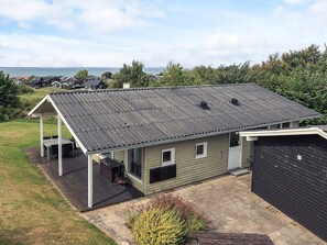A single-story house with a covered patio, a garage, and a view of the sea. - 6 Person Holiday Home in Brenderup Fyn (Middelfart)