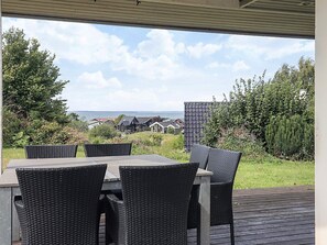 An outdoor patio with a table and chairs, overlooking a residential area and a body of water. - 6 Person Holiday Home in Brenderup Fyn (Middelfart)