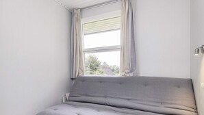 A room with a grey sofa, a window with curtains, and a wooden floor. - 6 Person Holiday Home in Brenderup Fyn (Middelfart)