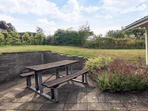 An outdoor picnic area with a metal table and benches, surrounded by a brick wall and greenery. - 6 Person Holiday Home in Brenderup Fyn (Middelfart)