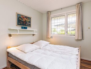 A single bed with a white duvet, a painting above it, and a window with curtains. - 6 Person Holiday Home in Brenderup Fyn (Middelfart)