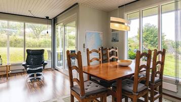 A dining area with a wooden table and chairs, a map on the wall, and large windows offering a view of the outdoors.