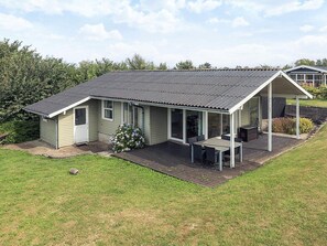 A single-story house with a covered patio, a small garden, and a neighboring building. - 6 Person Holiday Home in Brenderup Fyn (Middelfart)